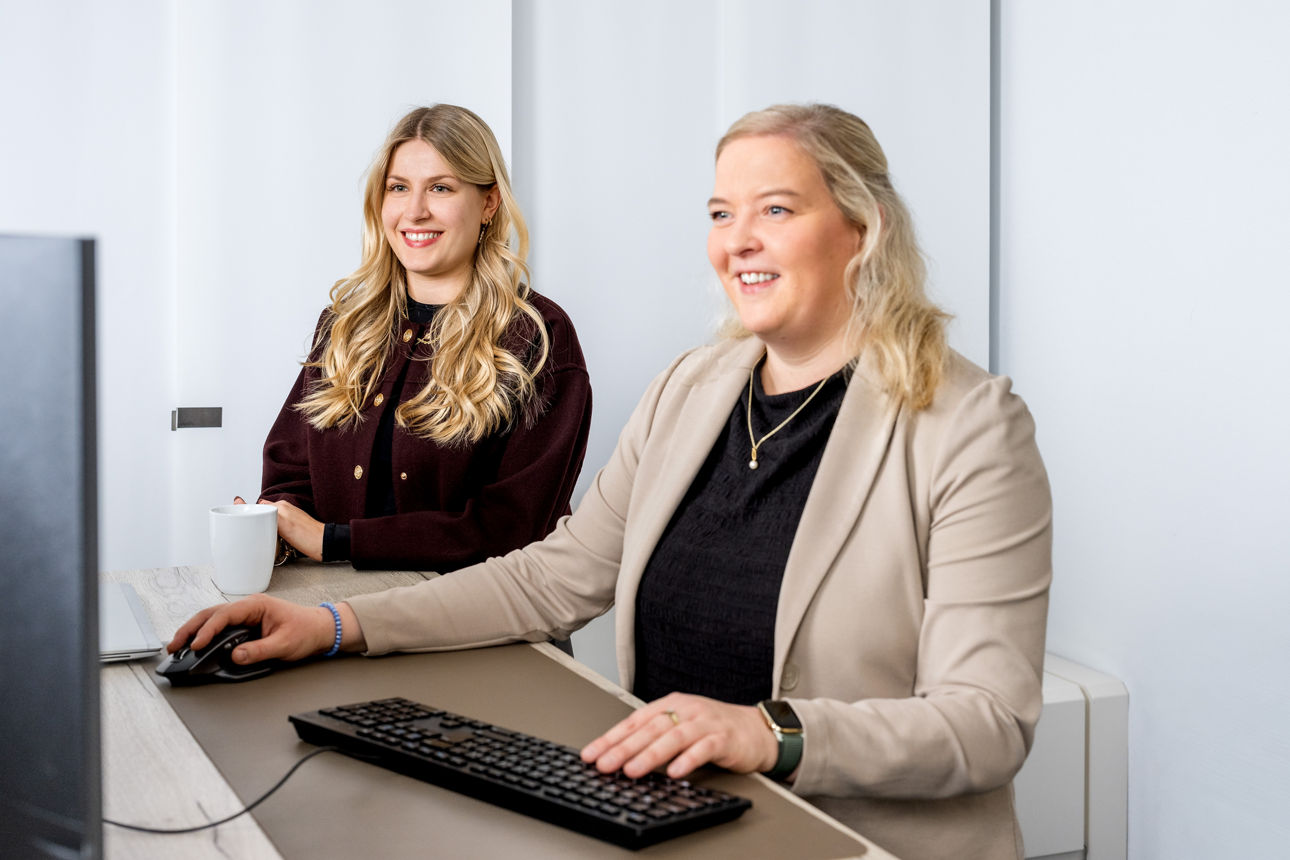 Zwei Frauen schauen auf einen Bildschirm.