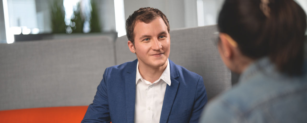 Ein Privatkundenberater im blaue Sakko und mit Laptop im Gespräch mit seiner Kundin.