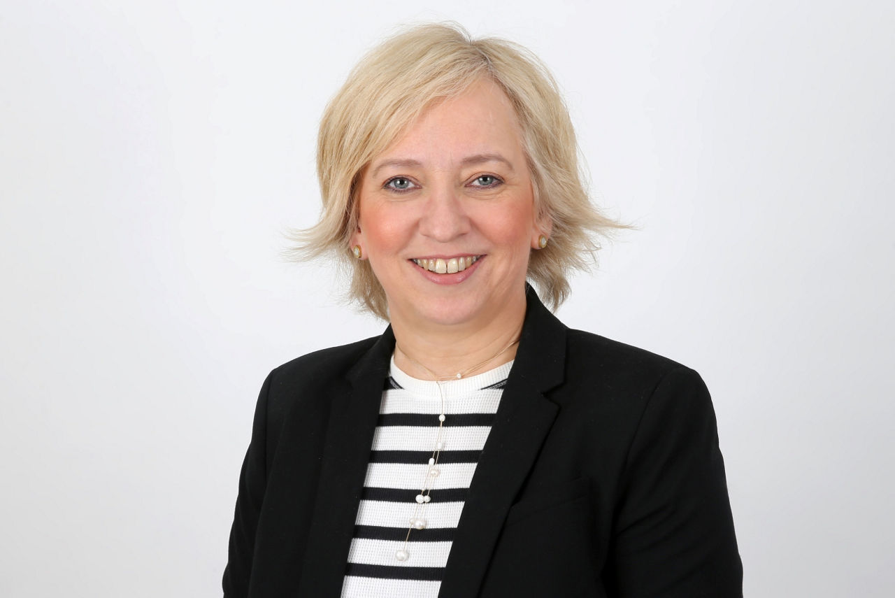 Eine lächelnder Frau schaut in die Kamera.