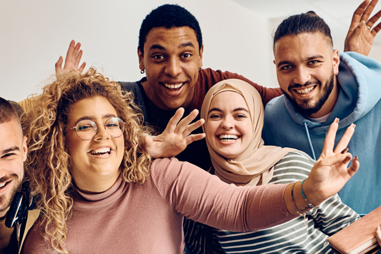 Gruppe aus jungen Erwachsnen lächenlnd in einem Flur