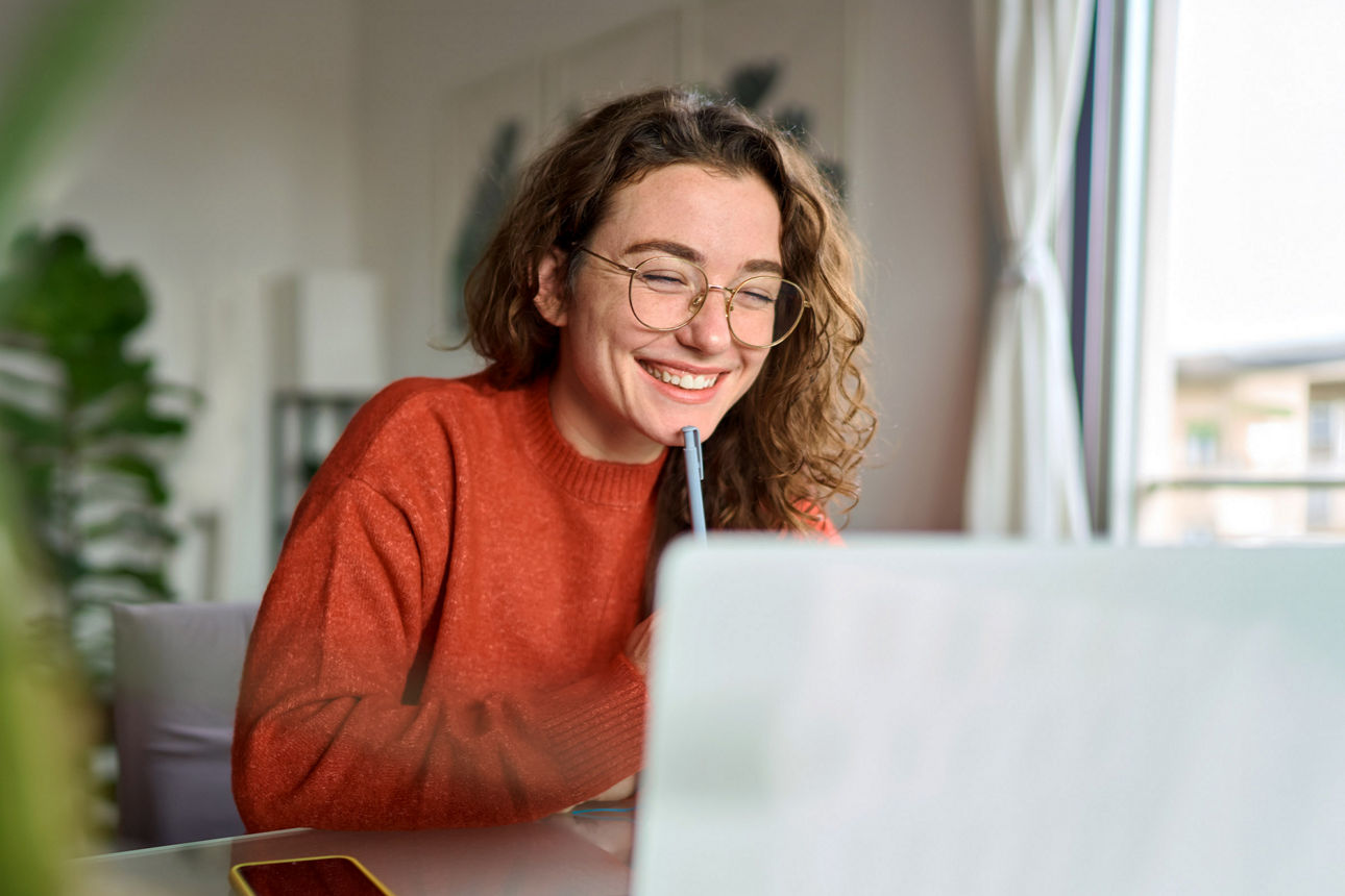 Junge Frau sitzt am Schreibtisch vor ihrem Laptop