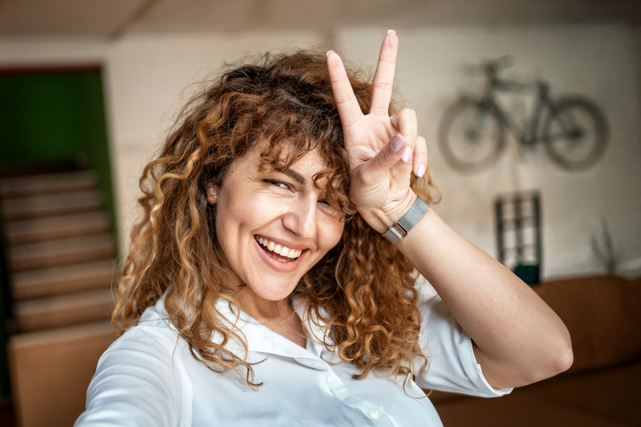 Junge Frau zeigt strahlend das Victory-Zeichen