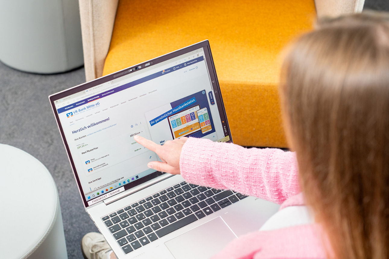 Geöffneter Laptop mit einer Übersicht und eine junge Frau zeigt auf den Bildschirm