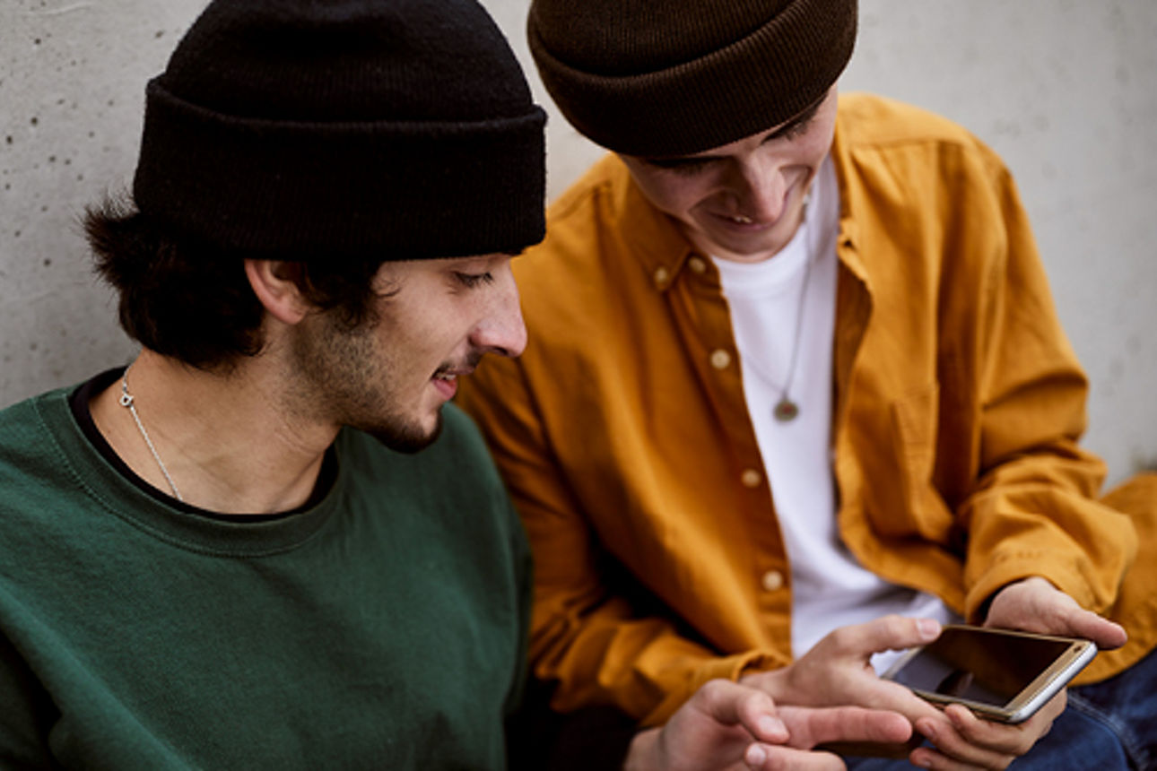 Zwei junge Männer schauen auf ihr Handy