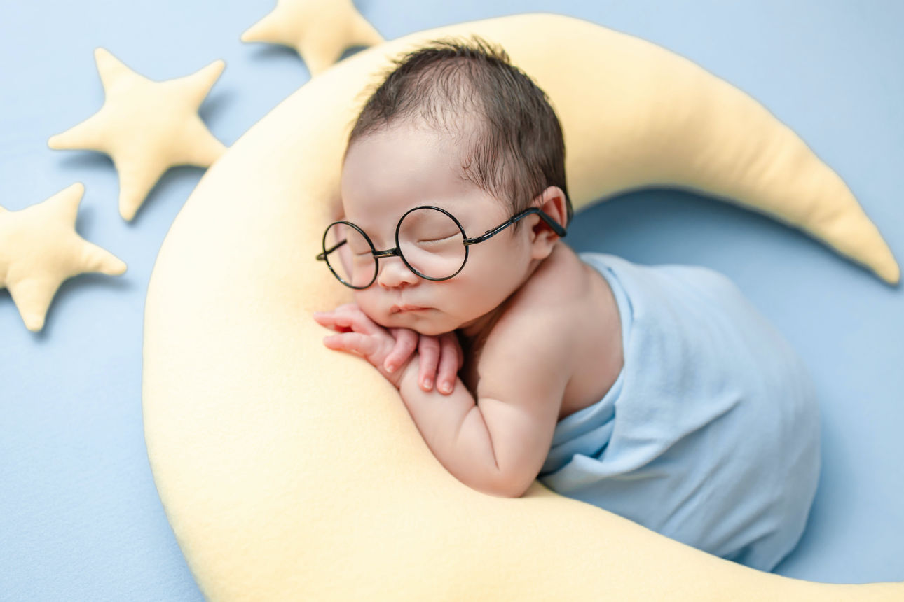 Baby liegt auf einem Kissen, das aussieht wie ein Halbmond