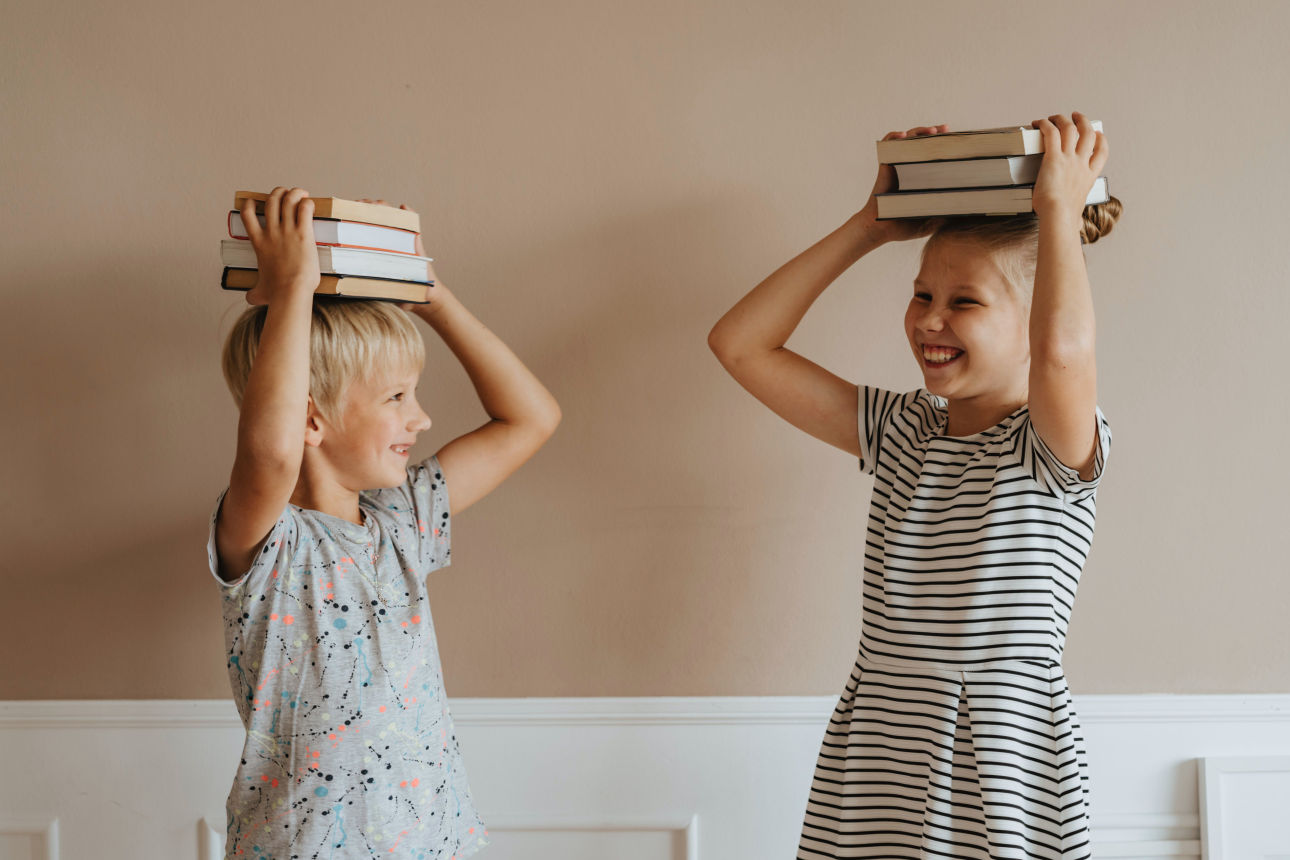 Kinder halten Bücher über dem Kopf und lachen