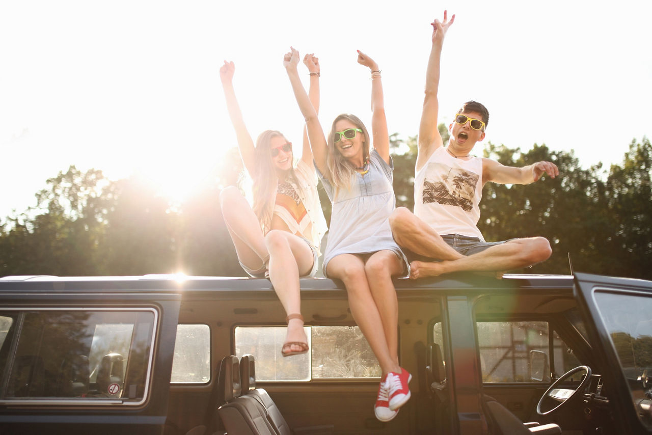 Junge Leute sitzen auf einem Camperbus im Sonnenuntergang
