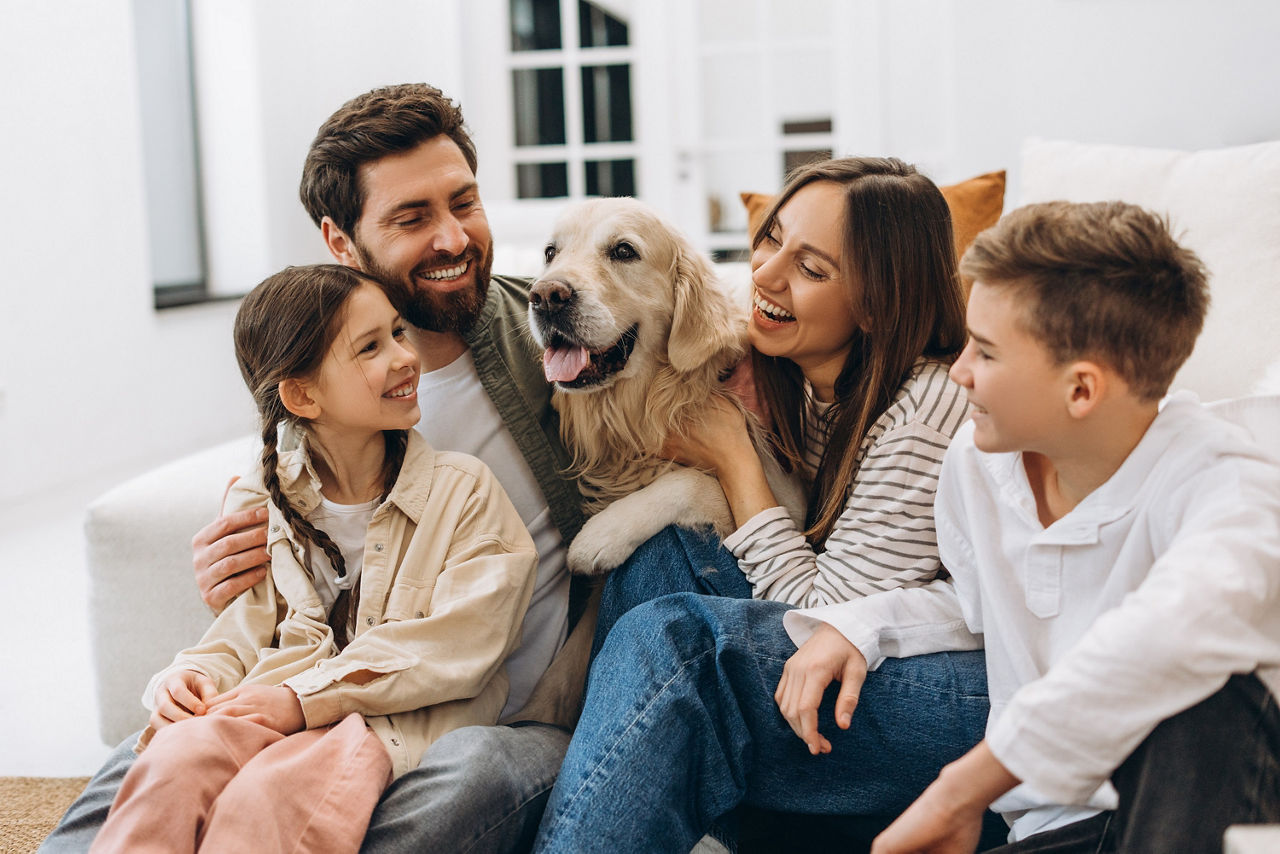 Junge Familie mit zwei Kindern und einem Hund lächeln