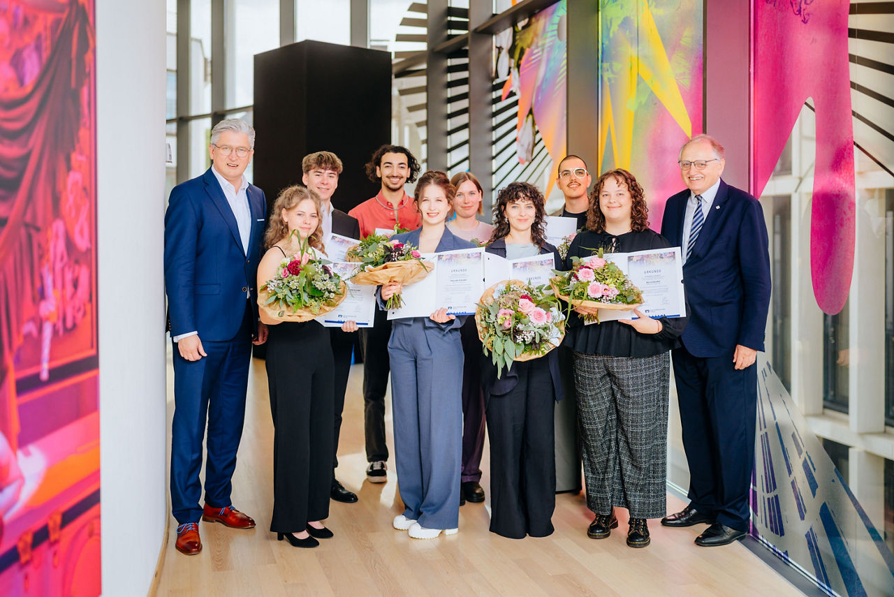 Vertreter der VerbundVolksbank OWL Stiftung und die Preisiträger des Förderpreises „Junge Kunst“ stehen im Theater Paderborn