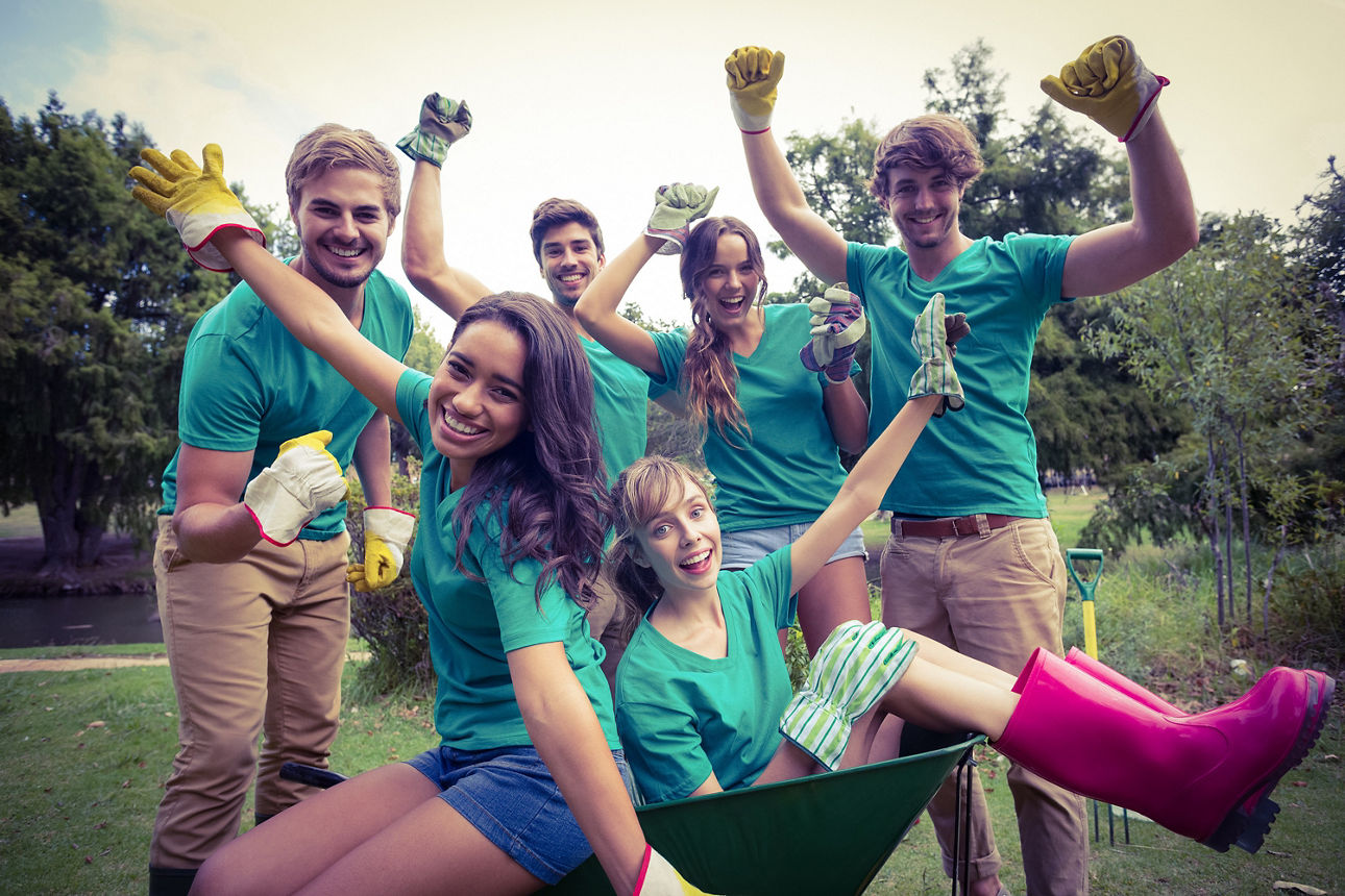 Eine Gruppe von Freunden, die in grünen T-Shirts bei der Gartenarbeit Spaß haben.