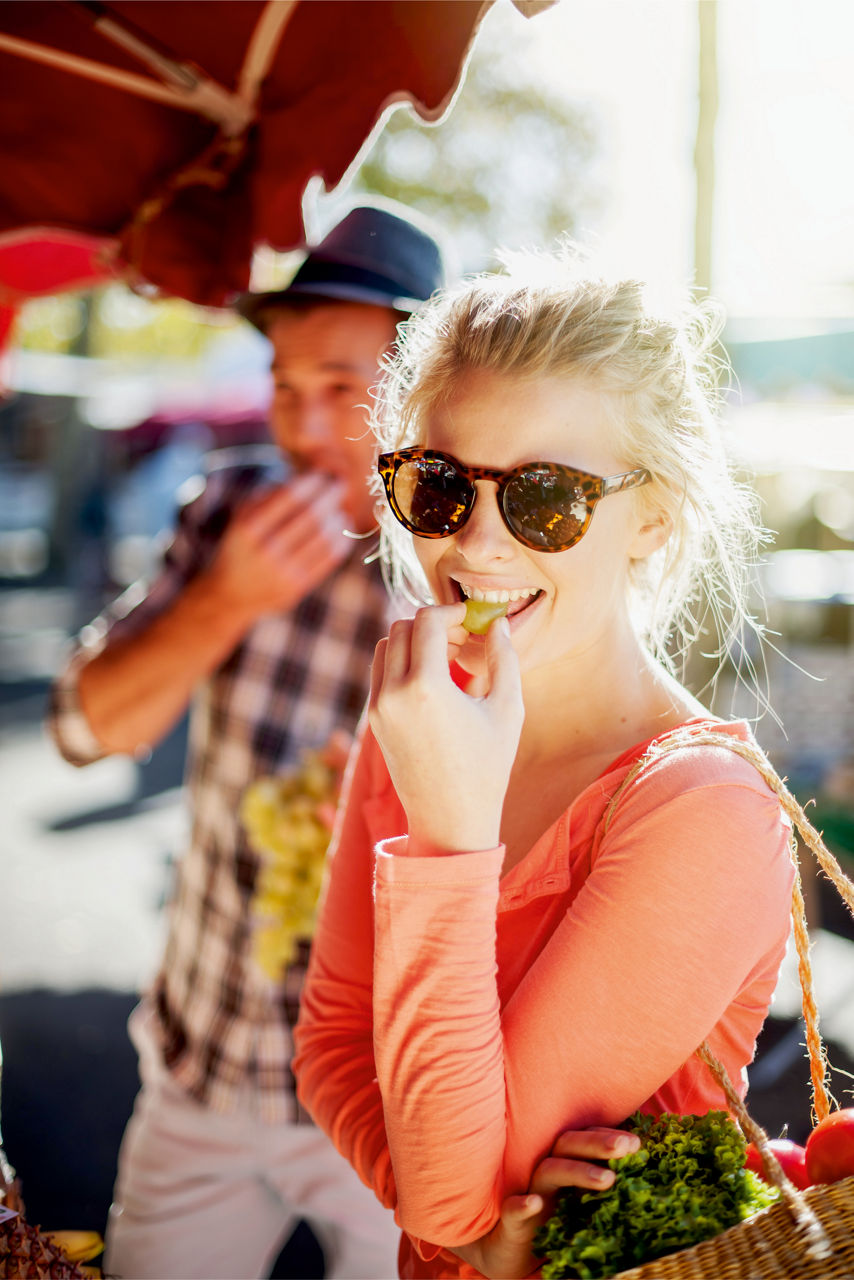 Junge Frau isst auf dem Markt eine Weintraube
