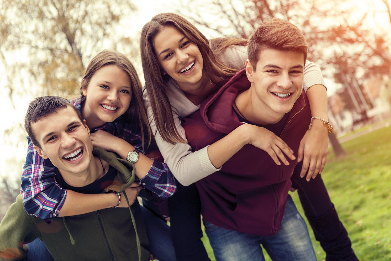 Zwei Jungs haben zwei Mädchen auf dem Rücken und lachen