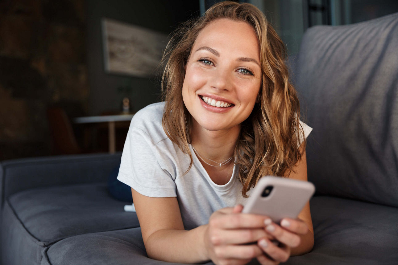 Junge Frau mit Handy auf dem Sofa