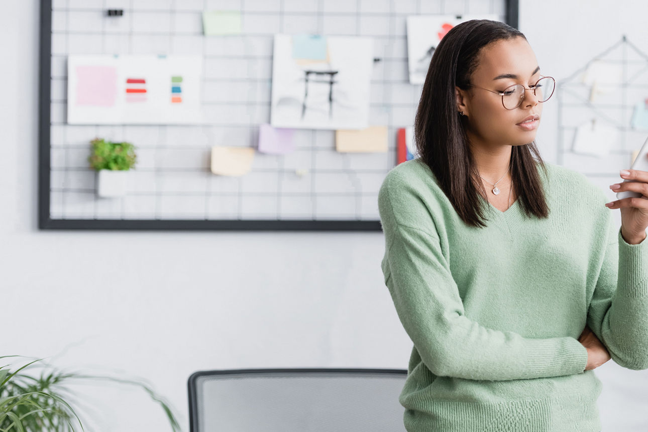 Junge Frau im Büro tippt Nachrichten auf dem Smartphone