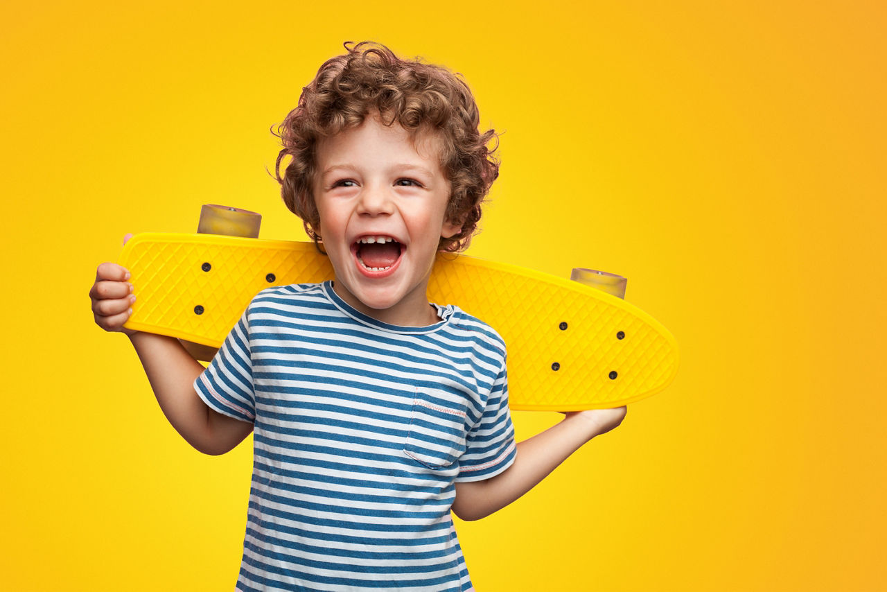 Kleiner Junge mit Skateboard lacht