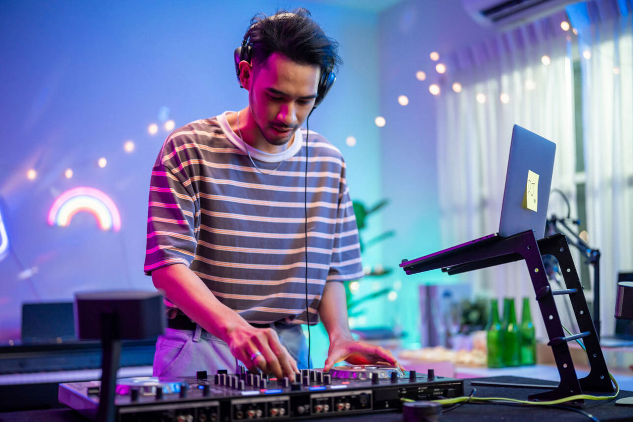 Junger Mann mixt eigene Musik am DJ-Pult.