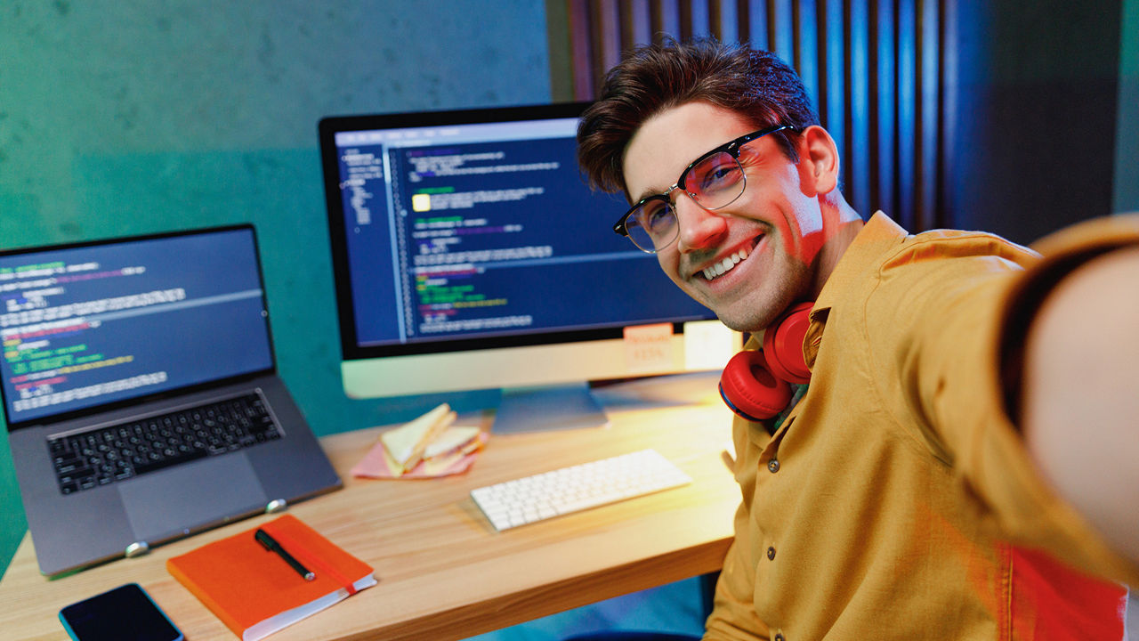 Selfie eines jungen Mannes, der am PC sitzt und Code schreibt