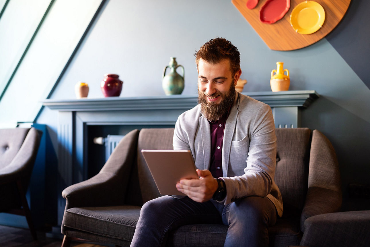 Junger Geschäftsmann, der ein Tablet in der Hand hält und lächelt