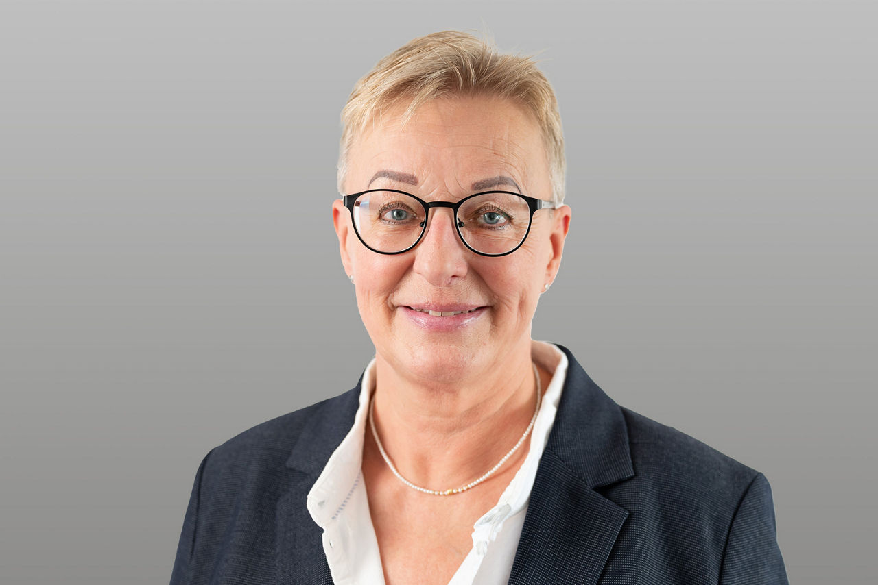 Servicemitarbeiterin Angela König vor grauen Hintergrund