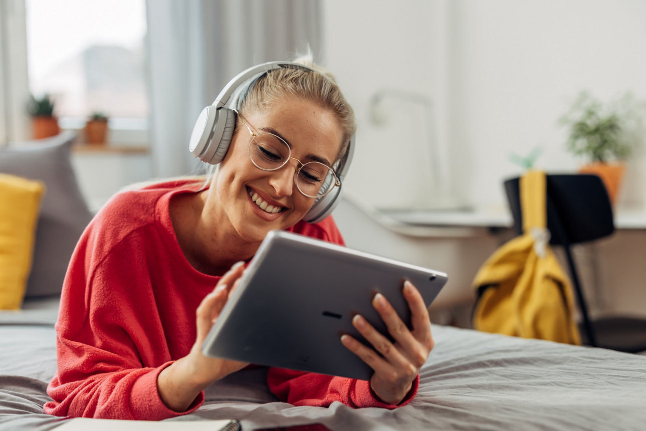 Eine Frau liegt entspannt auf dem Bett und spricht per Tablet mit dem KundenBeratungsCenter.