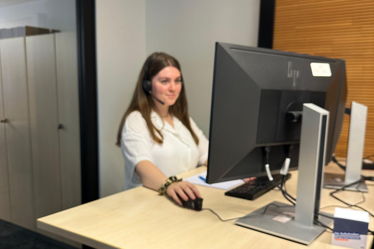 Frau mit Kopfhörer vor einem Computer Bildschirm