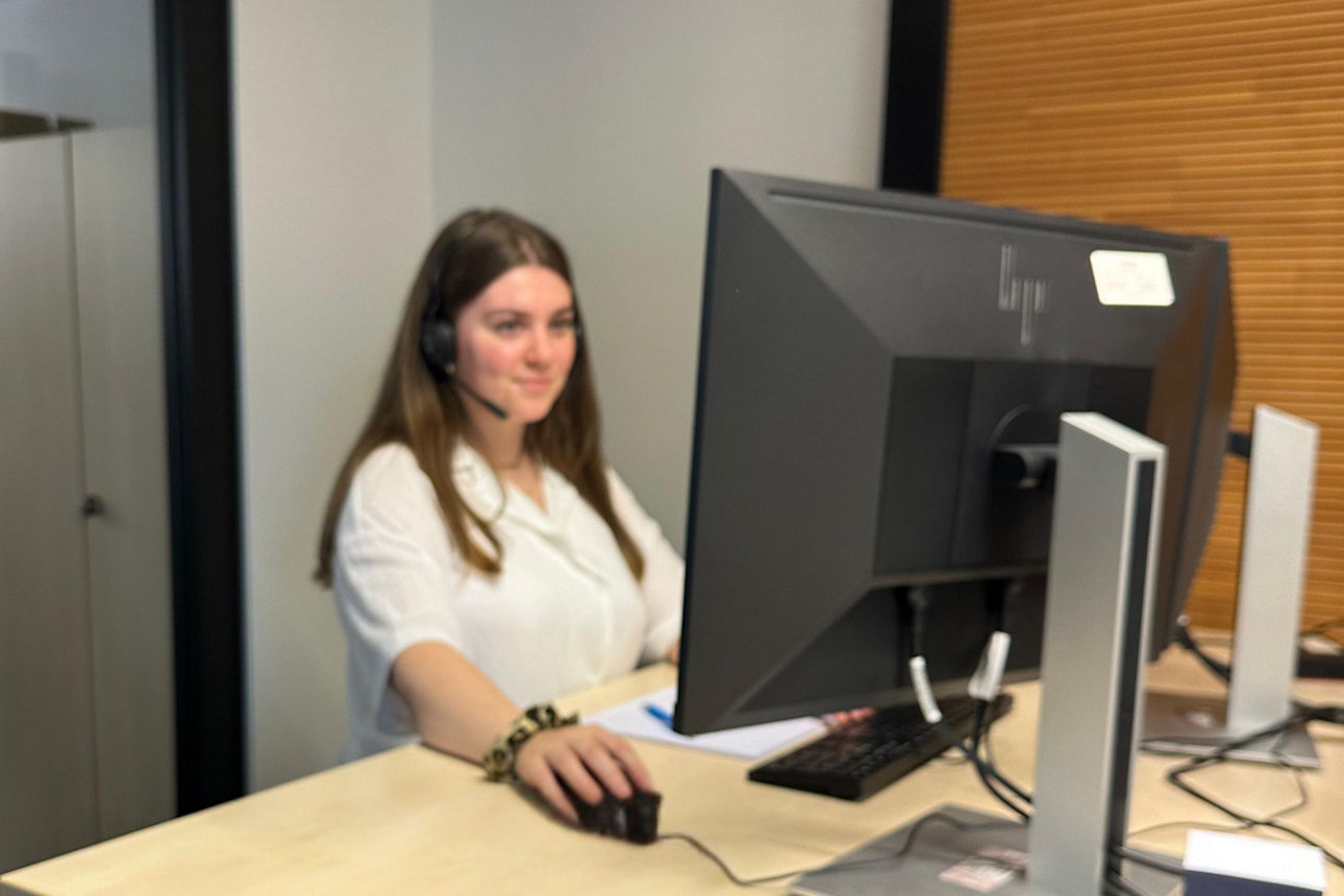 Frau mit Kopfhörer vor einem Computer Bildschirm