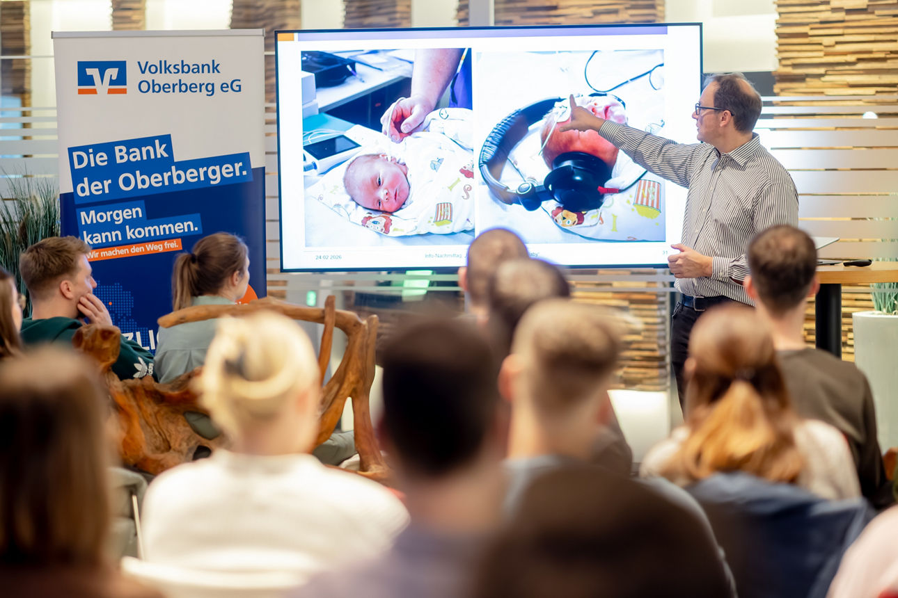 Publikum bei einem Vortrag in der Volksbank Oberberg eG: Personen im Vordergrund verfolgen die Präsentation eines Referenten