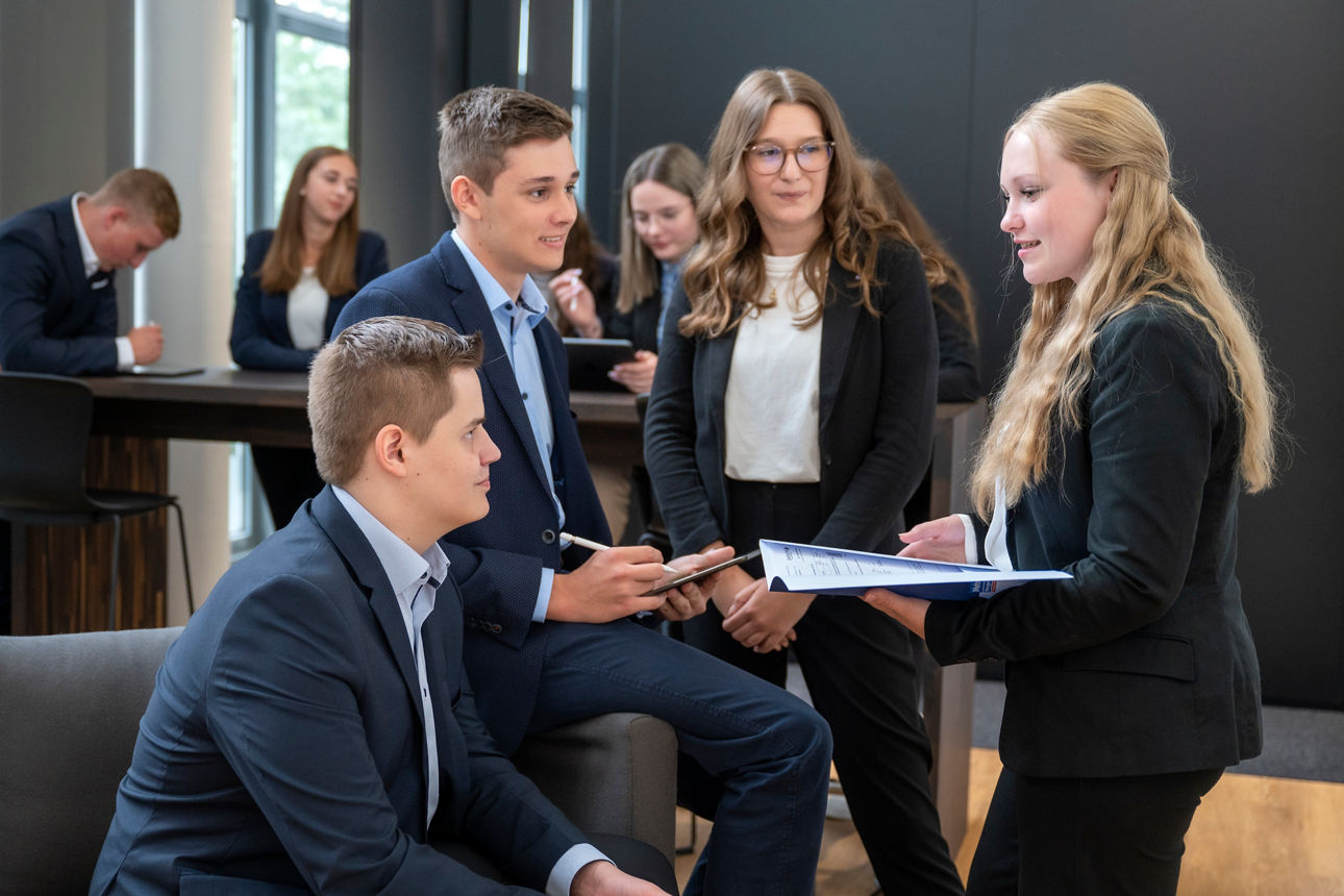 Drei lachende Menschen stehen vor einer blauen Wand mit dem Schriftzug „Wir sind meine Bank.”