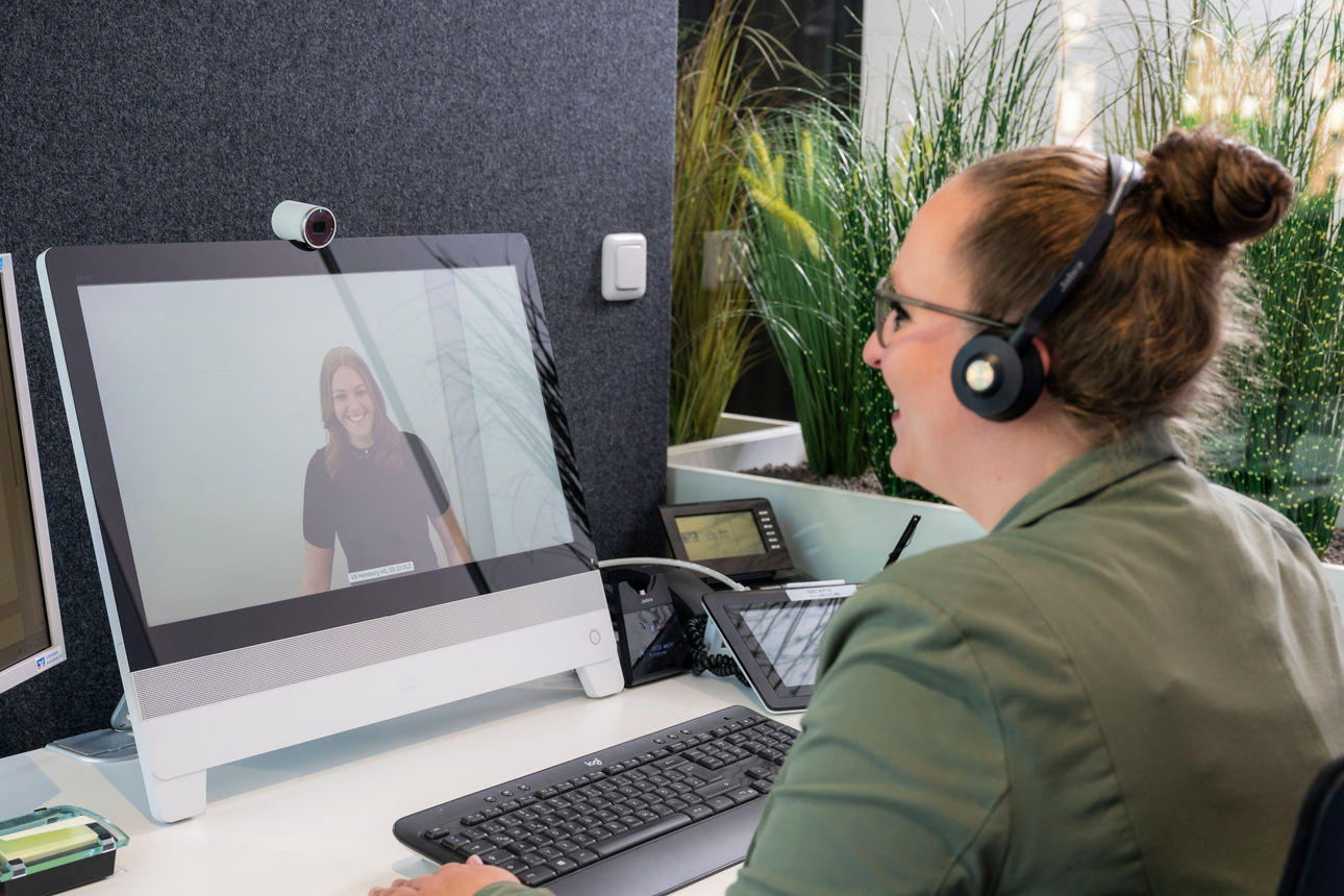 Junge Frau ist in einer digitalen Beratung und lächelt in Richtung der Kundin.
