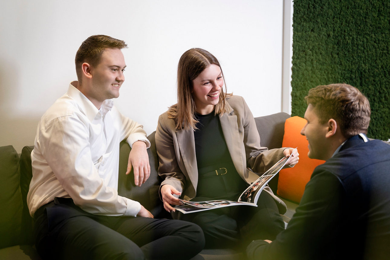Drei Personen, die auf einem Sofa sitzen und eine Broschüre lesen.