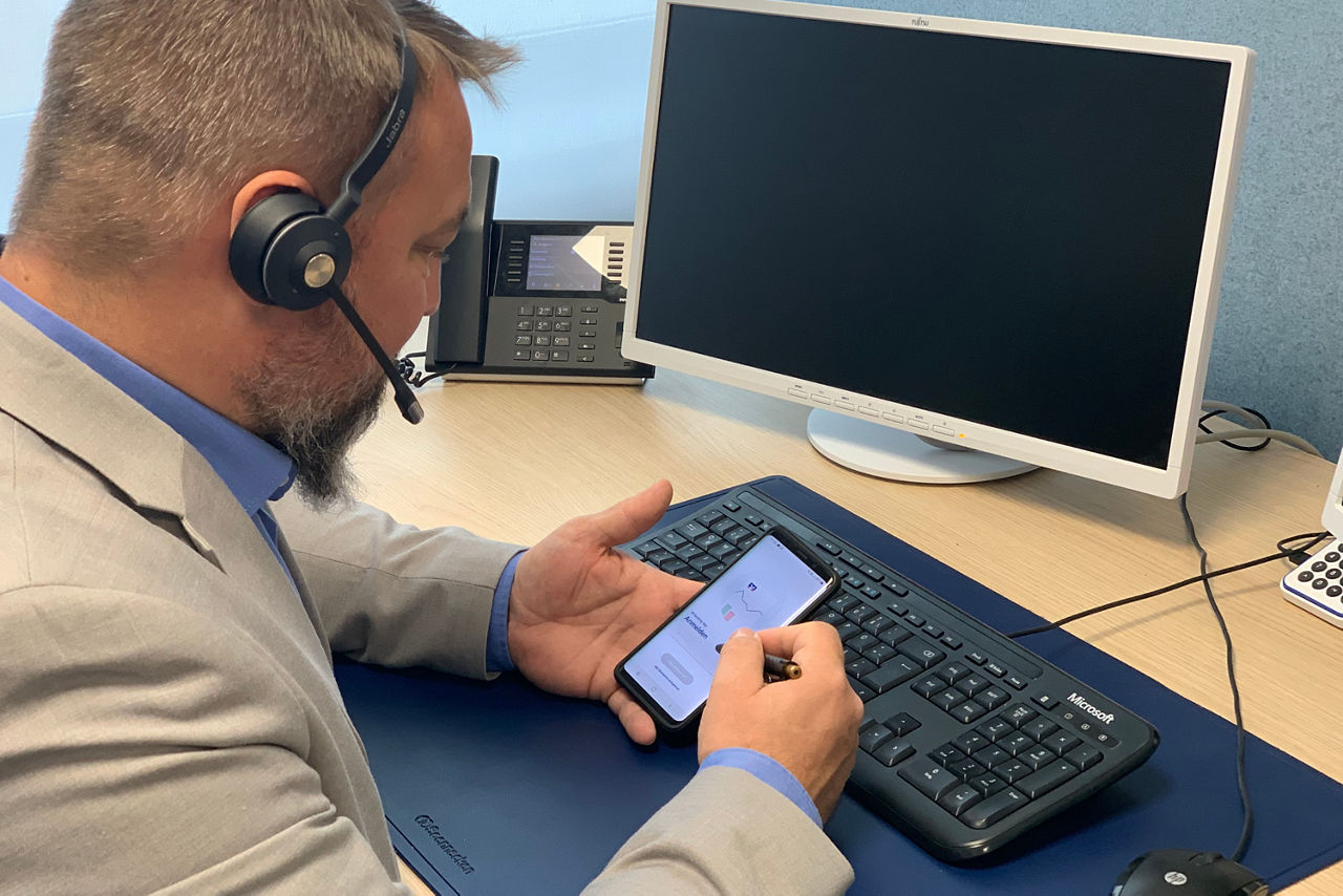 Mitarbeiter mit Headset und Online-Banking am Smartphone