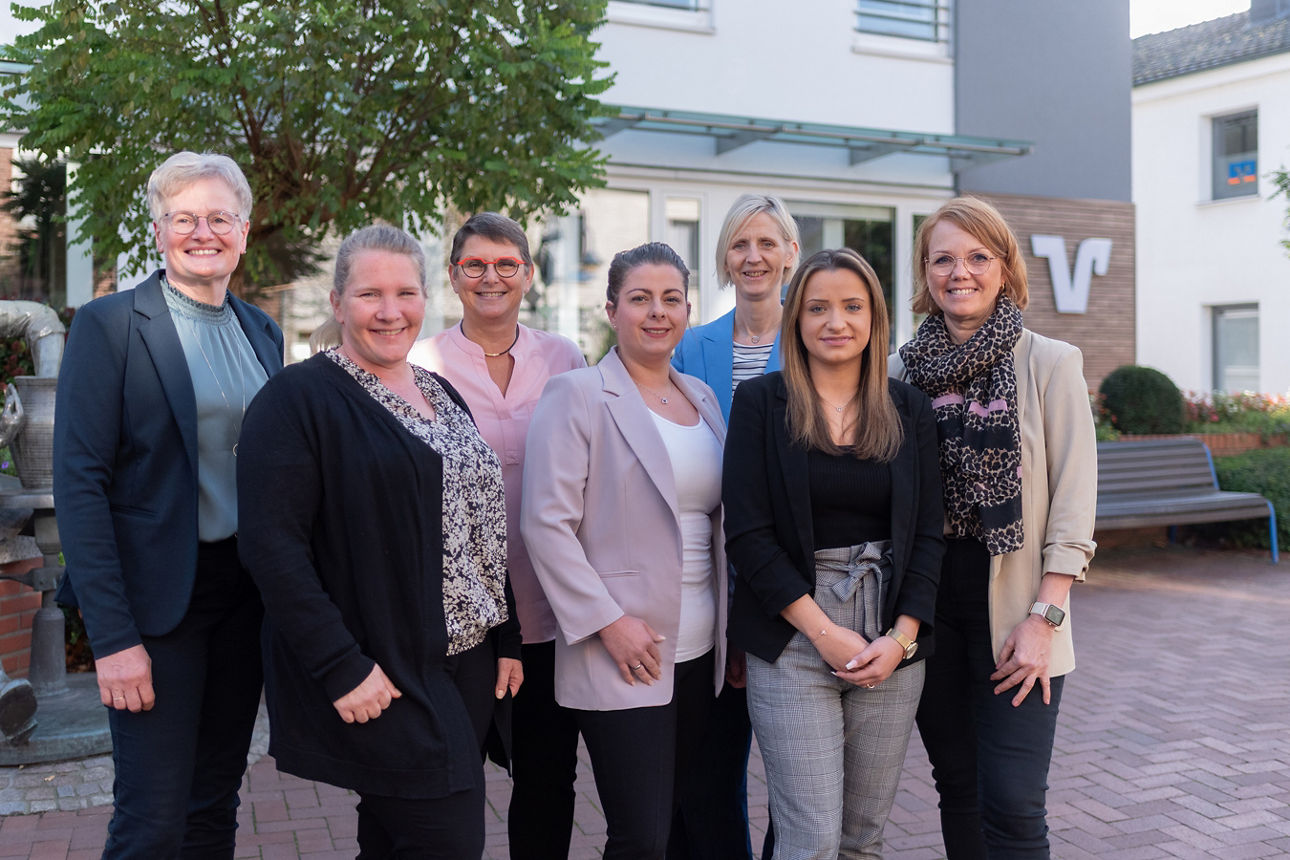 Unser Volksbank Schermbeck Telefonteam bestehend aus 7 Frauen vor dem Gebäude der Volksbank Schermbeck.