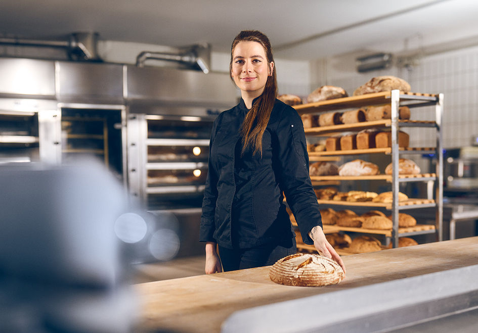 Eine Frau in Arbeitskleidung steht in einer Backstube 
