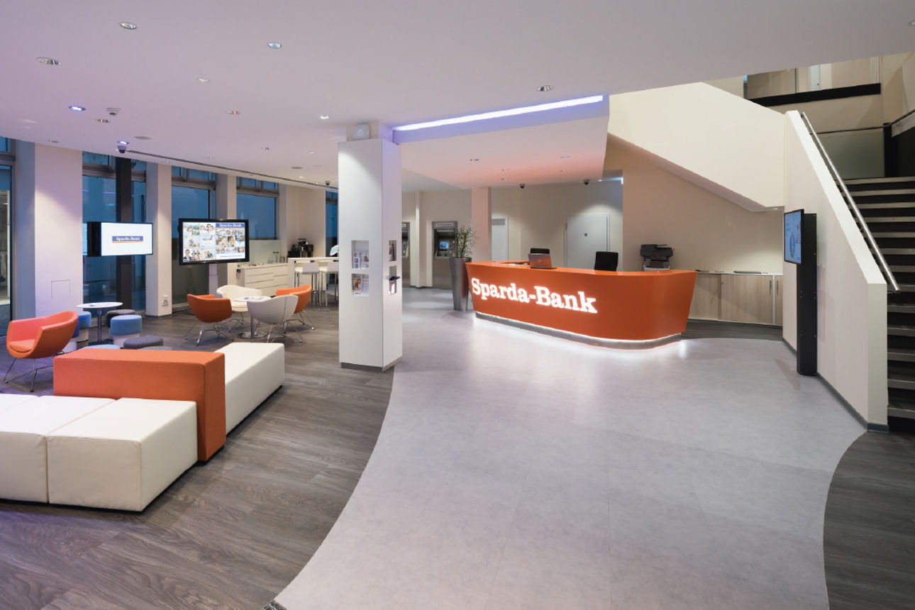 Eine Filiale der Sparda-Bank von innen, mit Schaltern und verschiedenen Sitzgelegenheiten