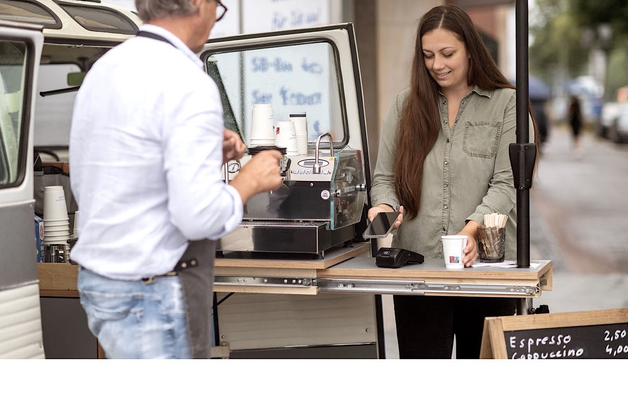 Eine junge Frau bezahlt mit Ihrem Handy