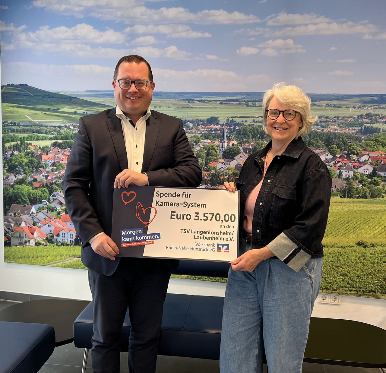 Zwei Erwachsene halten einen Spendenscheck in der Hand.