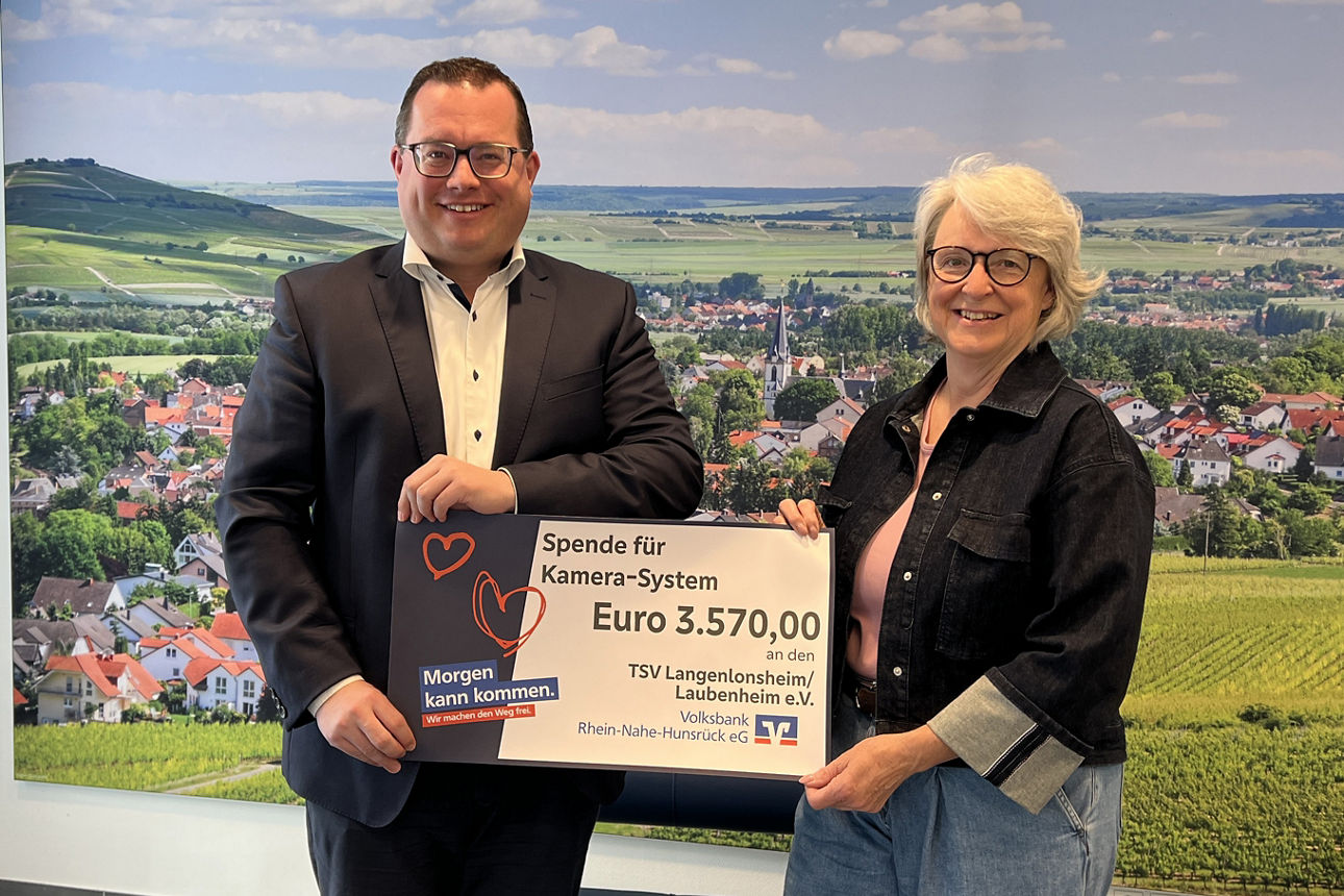 Zwei Erwachsene halten einen Spendenscheck in der Hand. 