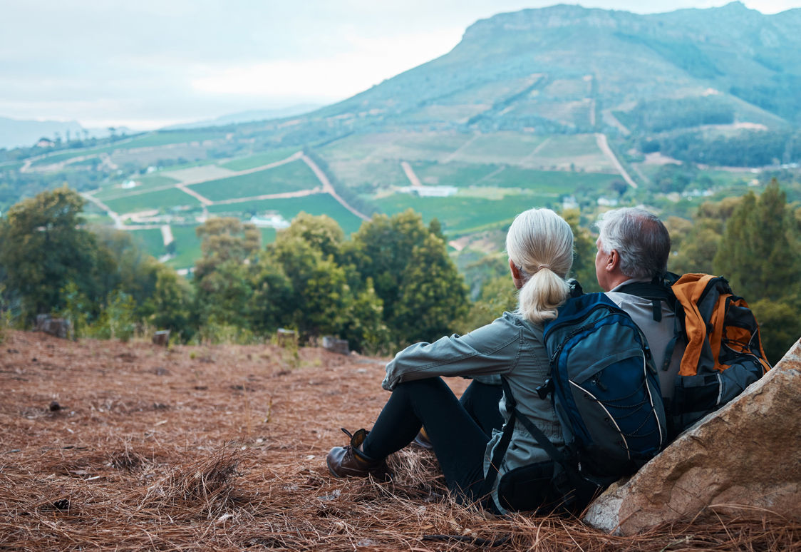 Ein äteres Paar sitzt auf dem Berg und genießt die Aussicht.
