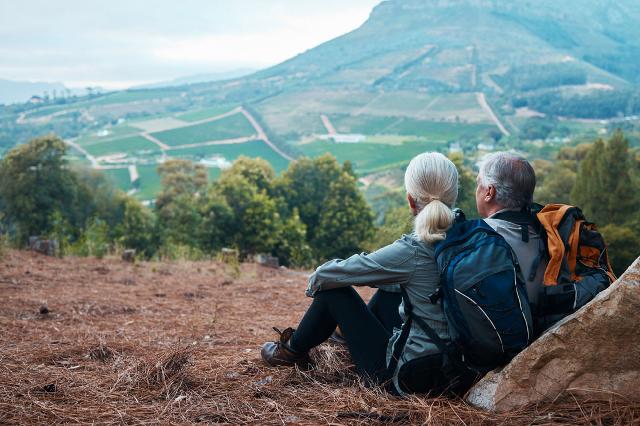 Ein äteres Paar sitzt auf dem Berg und genießt die Aussicht.