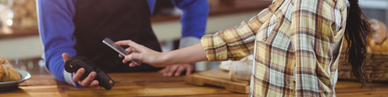 Frau hält Handy an Kartenlesegerät