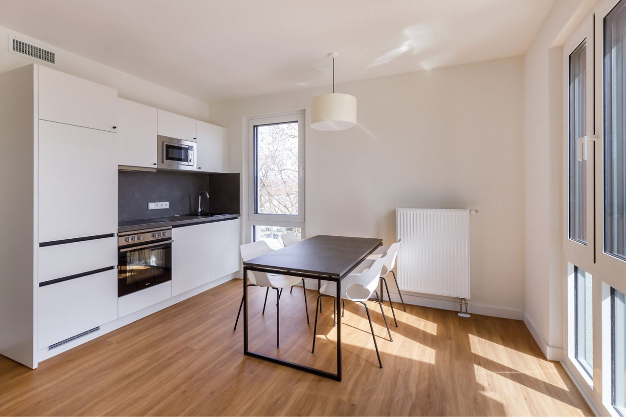 Innenansicht einer möblierten Wohnung mit weißer Küchen und Esstisch