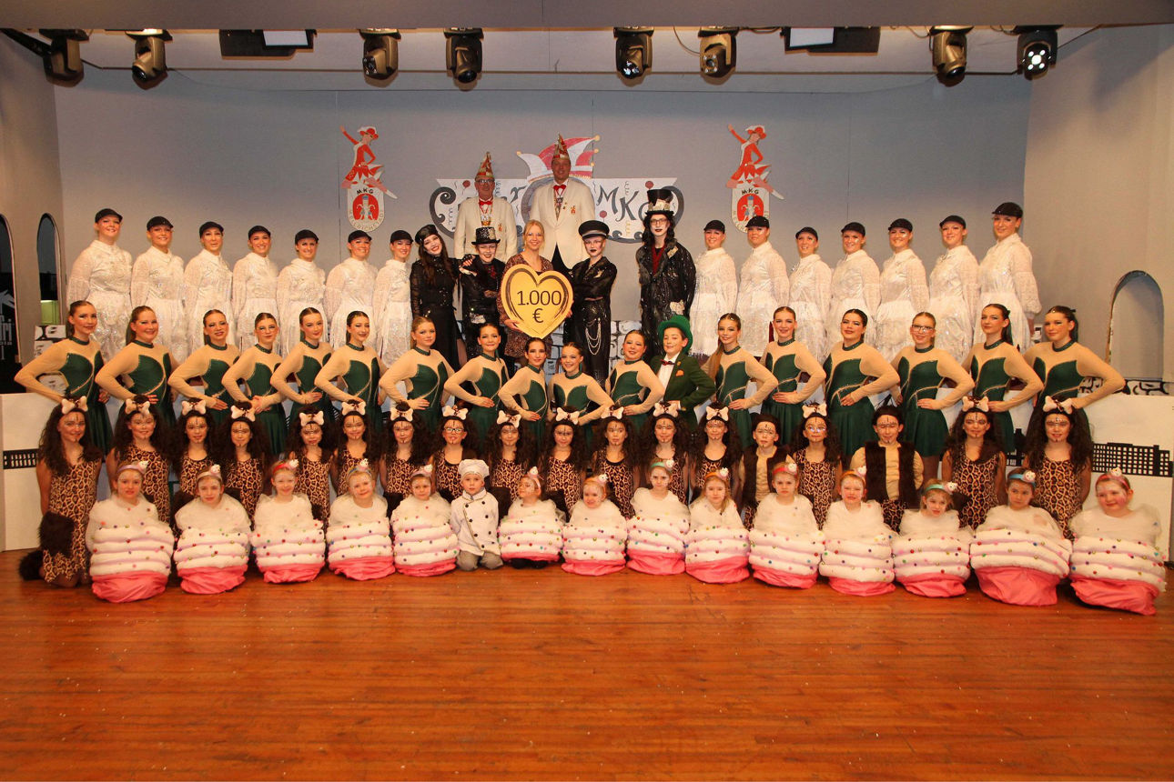 Das Bild zeigt eine große Gruppe von Menschen in verschiedenen, thematisch abgestimmten Kostümen auf einer Bühne, vermutlich 