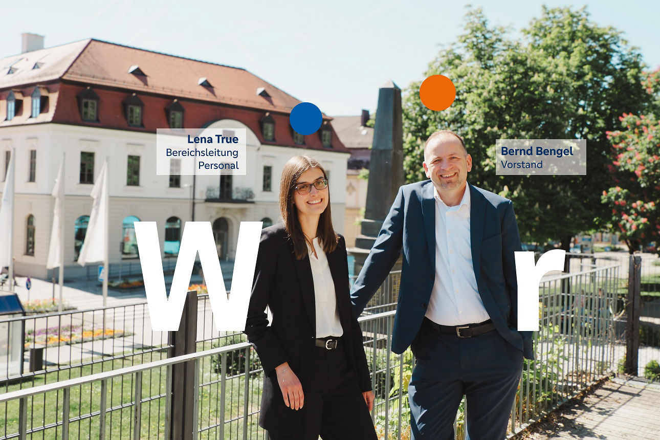 Zwei Mitarbeiter stehen lächelnd vor dem Bankgebäude in Neuburg