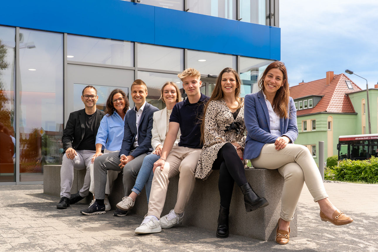 Personengruppe sitzend auf einer Mauer