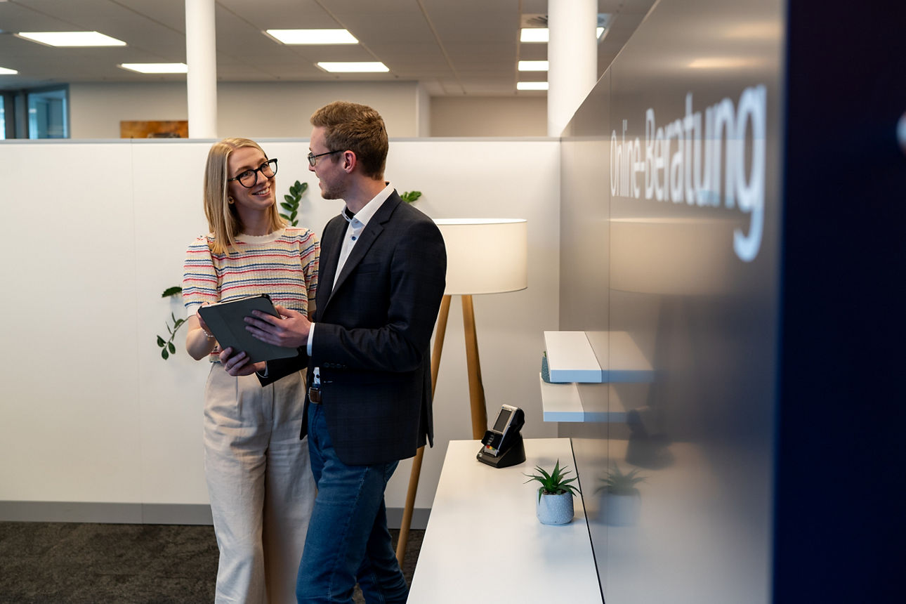 Mitarbeiterin und Mitarbeiter schauen gemeinsam auf ein Tablet