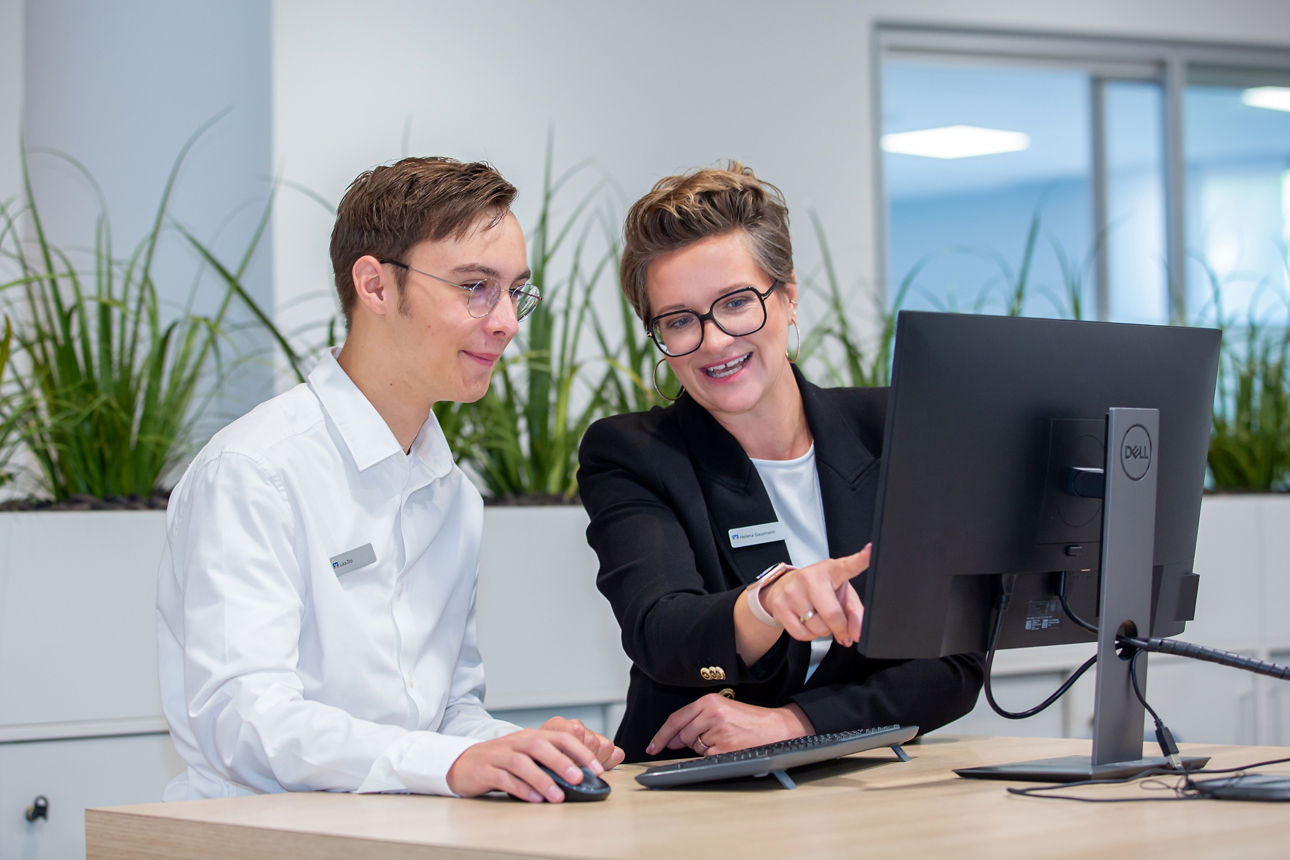 2 Personen die gemeinsam am Monitor arbeiten und sich etwas zeigen