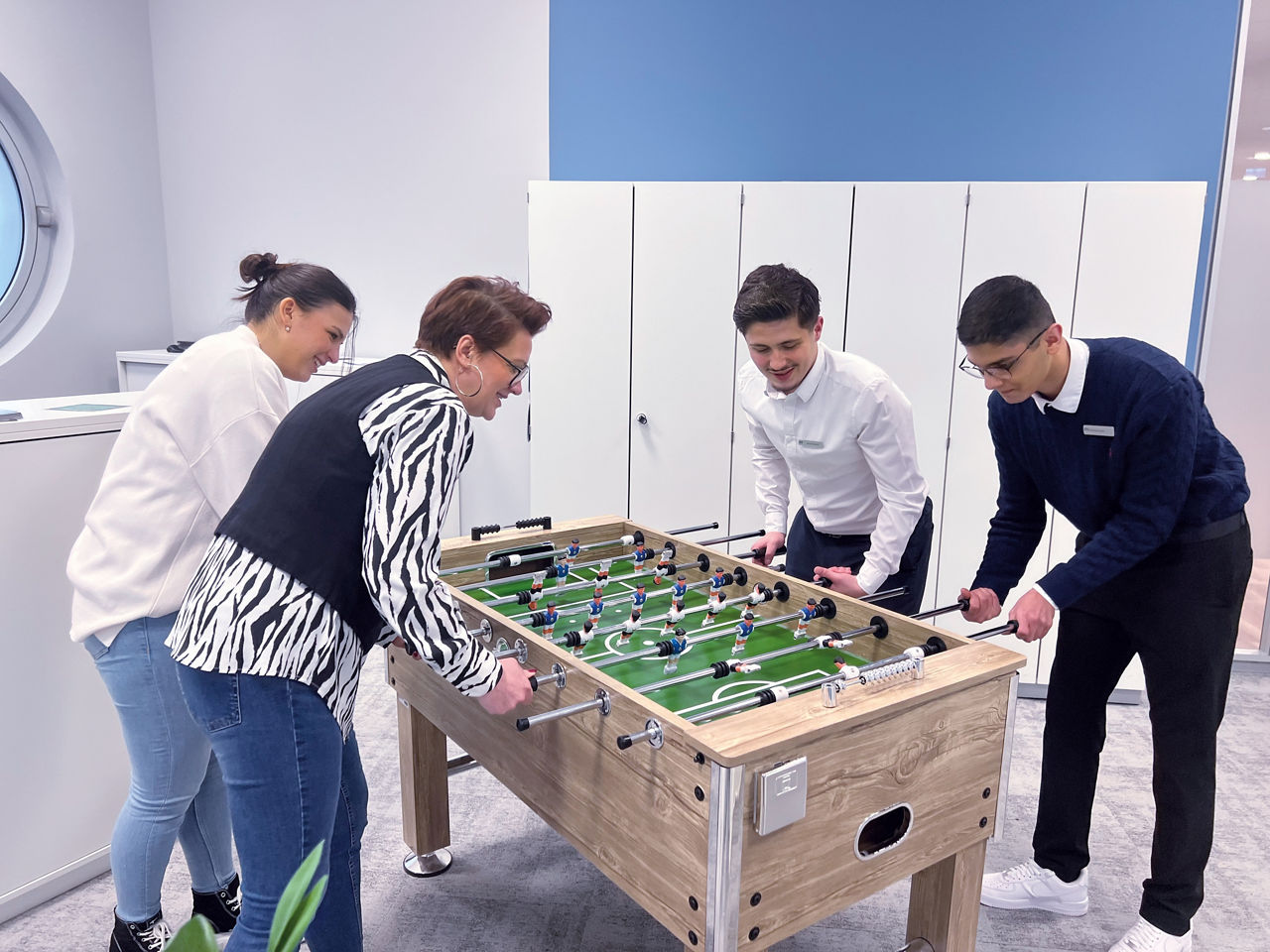 Vier Personen die gemeinsam Tischkicker spielen