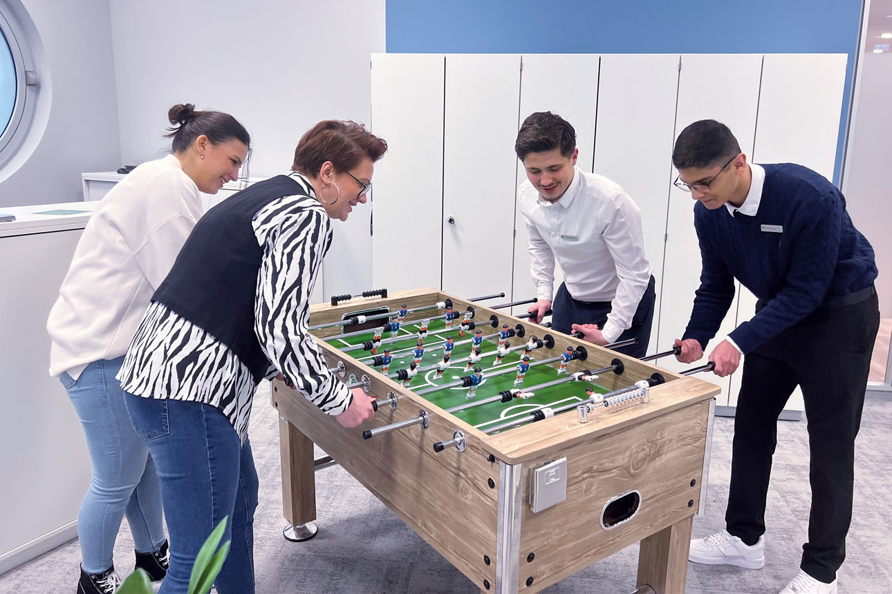 Vier Personen die gemeinsam Tischkicker spielen
