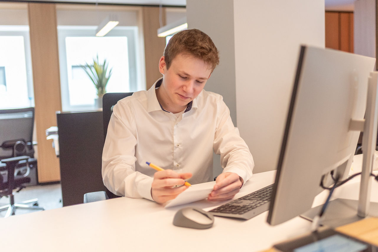 Auszubildender sitzend vor einem Monitor an einem Arbeitsplatz