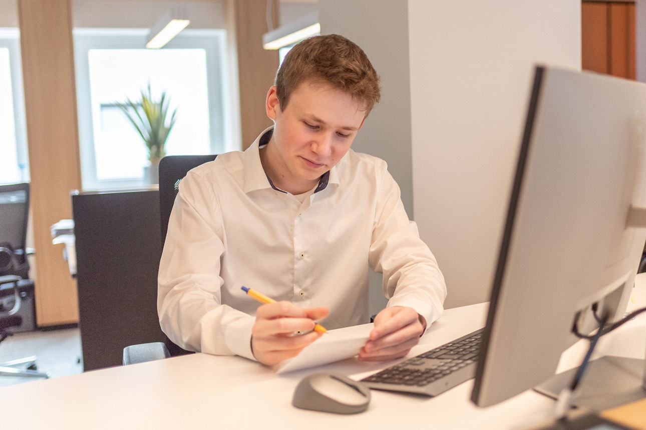 Auszubildender sitzend vor einem Monitor an einem Arbeitsplatz